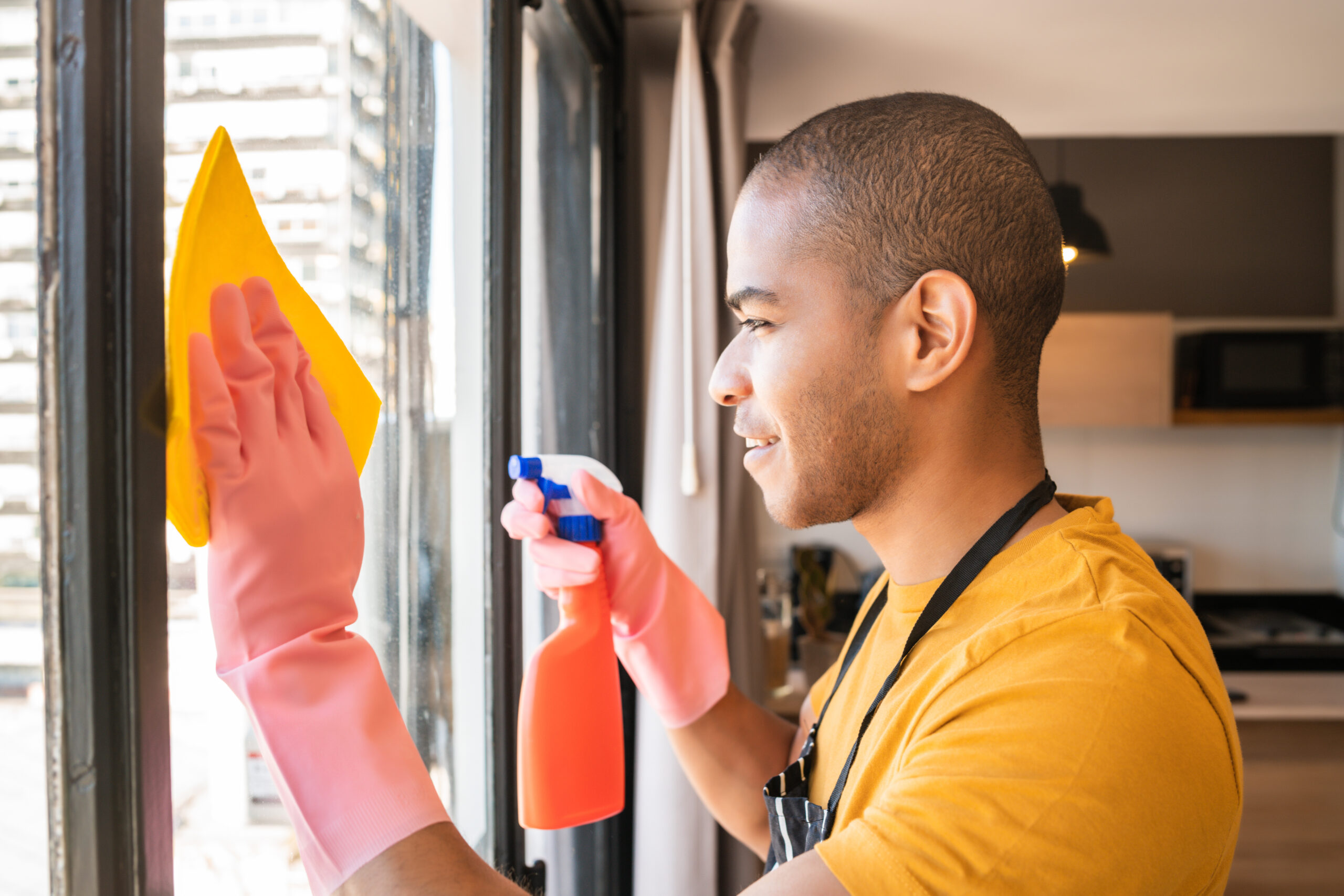 male housekeeper cleaning glass window at home.